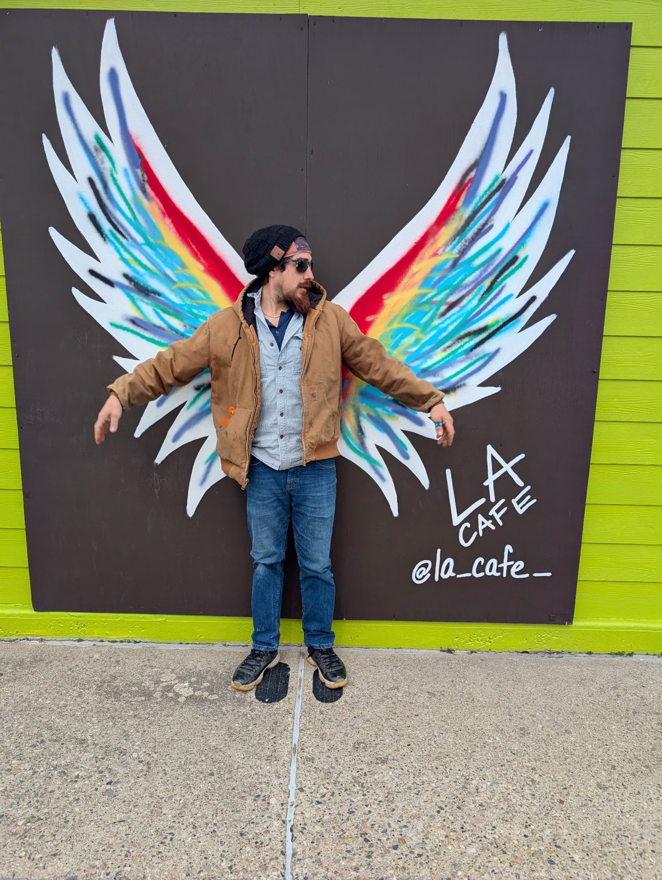A guest posing in front of the L.A. Cafe angel wings mural